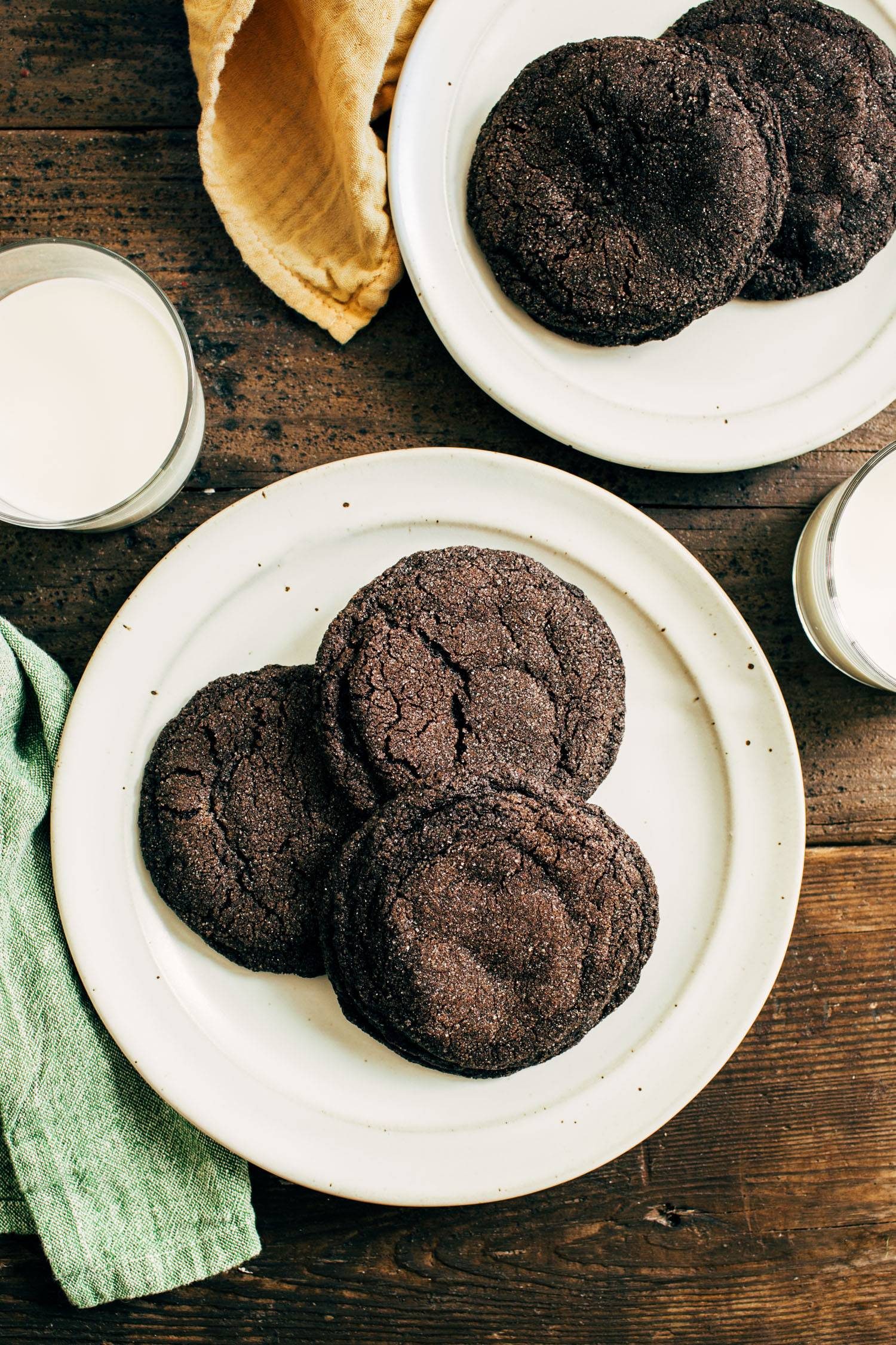 Dark chocolate cookies on a plate next to a glass of milk.