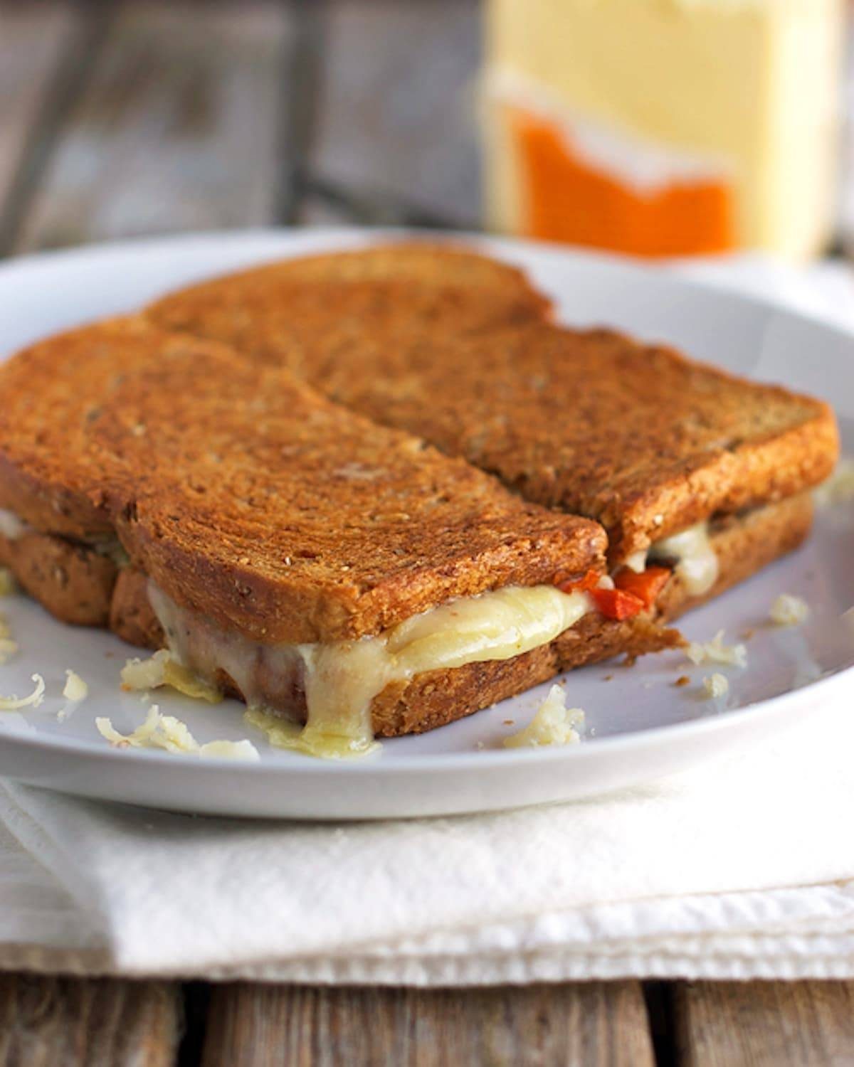 Three cheese grilled cheese sliced in half on a white plate.